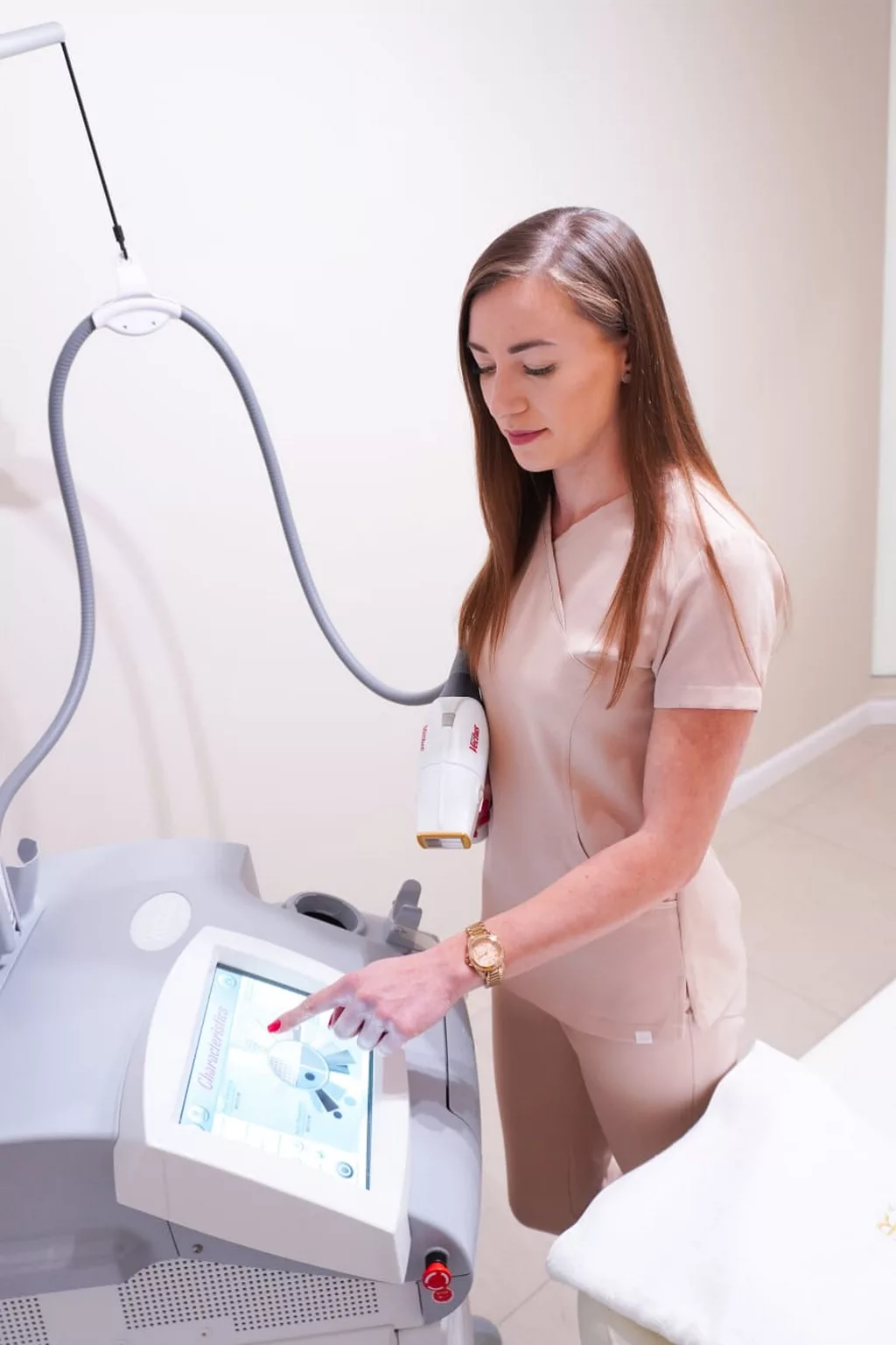 Patrycja Szubka obsługująca urządzenie do depilacji laserowej w gabinecie kosmetycznym Prestige Laser we Wrocławiu, ustawiająca parametry zabiegu na ekranie dotykowym.