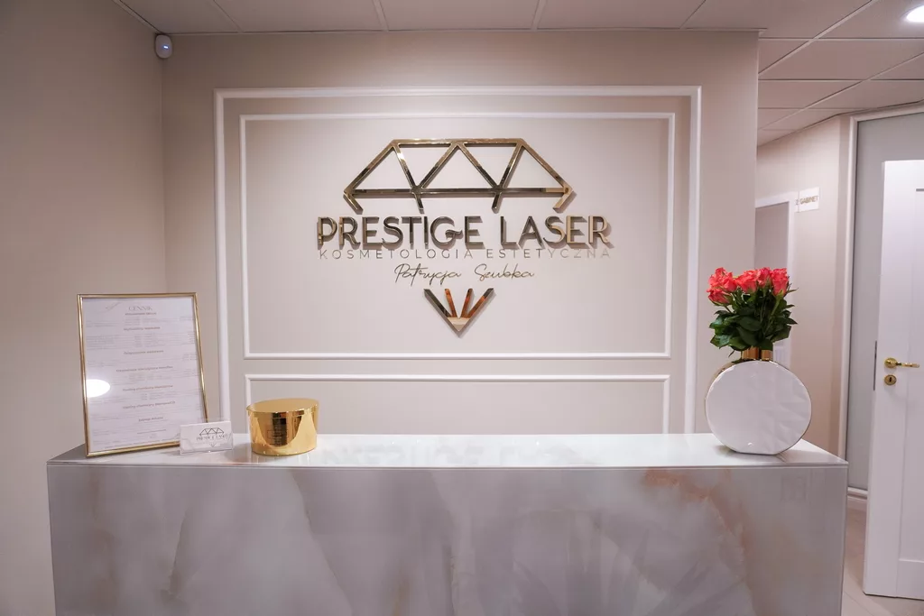 Recepcja salonu Prestige Laser Kosmetologia Estetyczna we Wrocławiu – eleganckie wnętrze z logo w złotej ramie i bukietem czerwonych róż na ladzie.