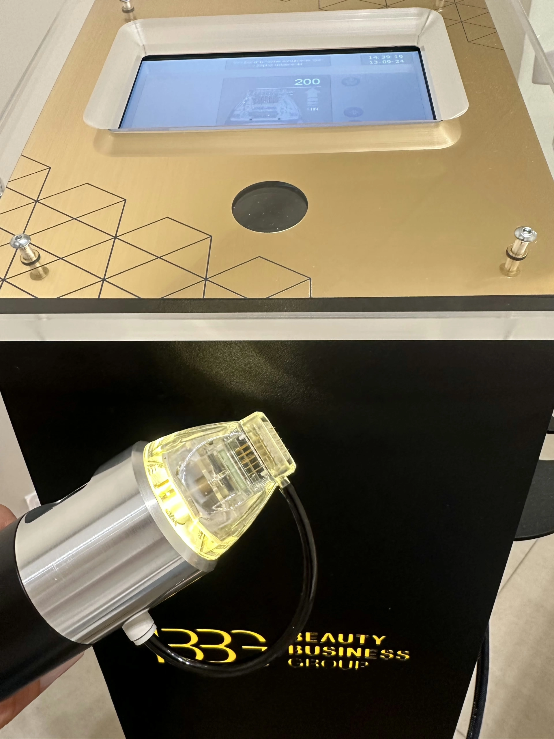 Urządzenie do radiofrekwencji mikroigłowej z panelem dotykowym i podłączoną głowicą zabiegową emitującą światło, używane w kosmetologii estetycznej.